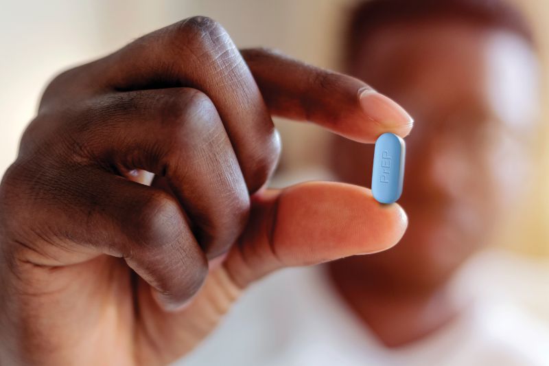 A person holding a pill of PrEP.