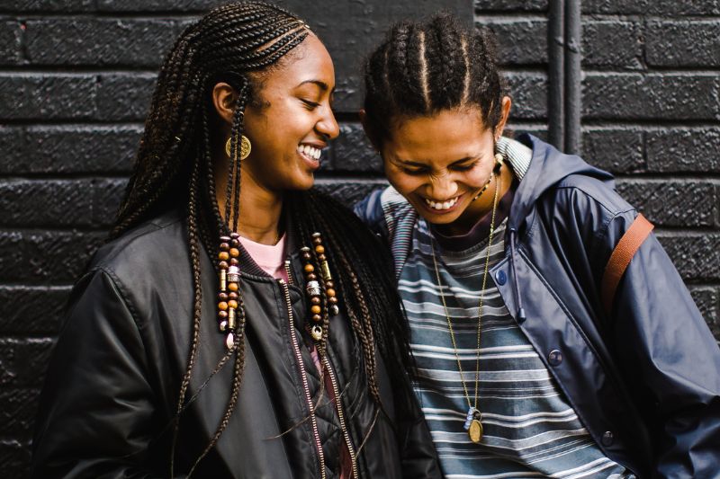 Two BIPOC women laughing and smiling