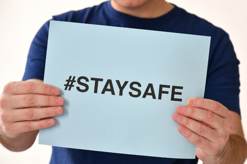 A person holding a piece of paper that says " #stay safe"