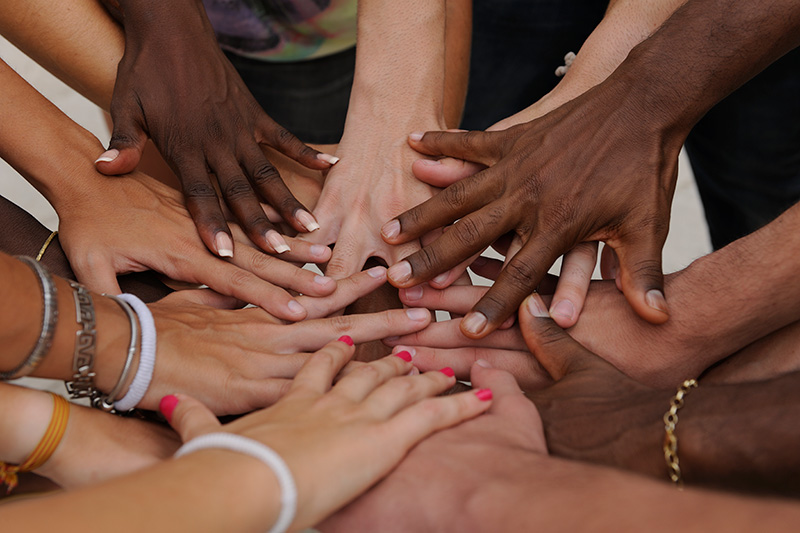 Diverse human hands showing unity by putting their hands together