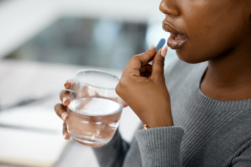 A dark-skinned woman taking a PrEP pill